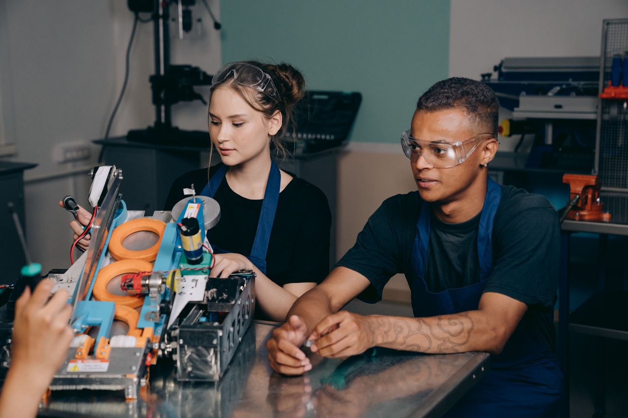 Mastering the First Impression: Your intriguing post title goes here Two young engineers collaborating on a complex machine in an industrial setting.